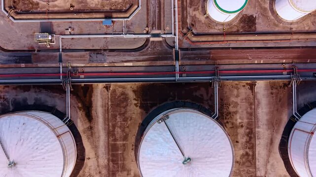 Larger and smaller tanks for fuel storage. Multiple pipeline connect the silos at oil refinery plant. Top view.