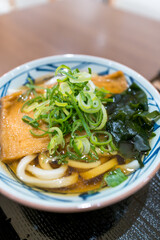 きつねうどんのアップ、ねぎとわかめ添え（和食・背景ボケ）