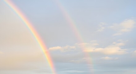 Fototapeta premium Vibrant double rainbow in cloudy sky with warm sunlight