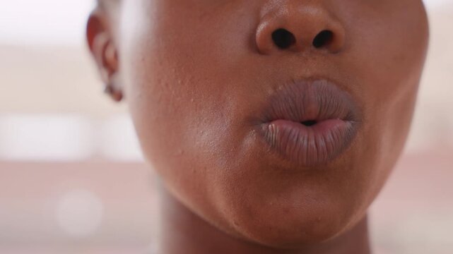 black woman opera trainee practicing vowels, closeup mouth and lips with visible moisture, focused projection and diction drills under stadium roof light, concentrated training for precision