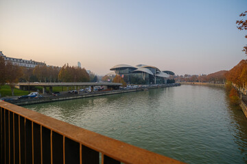 Iconic Justice House building with unique mushroom shaped roofs located on the bank of Mtkvari river in Tbilisi during a calm autumn evening with city bridge and trees. © Microscope