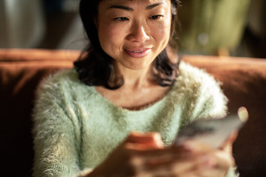Smiling woman using smartphone at home