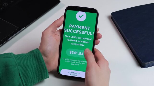 Close-up of smartphone screen with successful bill payment confirmation. User just paid utility services through a mobile banking app. Vibrant green interface with success animation. Ideal for