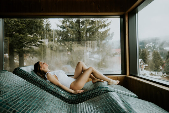 Relaxing woman enjoys peaceful spa experience on warm stone bed with scenic mountain view