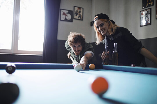 Friends playing pool and drinking beer in a bar