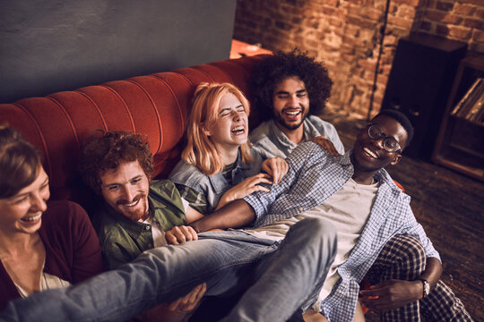 Group of friends laughing on sofa at home