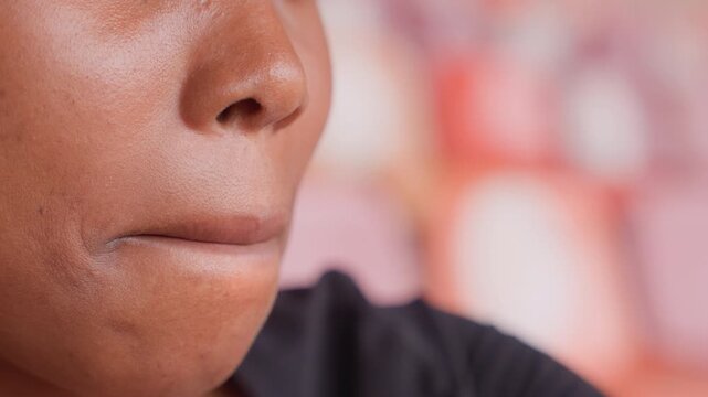 Sideprofile black woman with chapped lips, flaky skin, muted background, contemplative expression, urban cafe vibe, candid health closeup, skincare concern captured for awareness