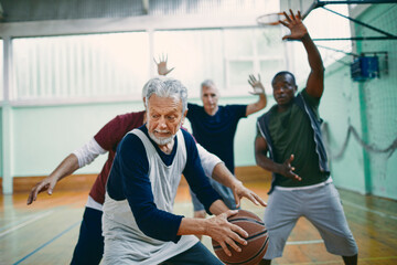 Senior men playing basketball in indoor gym