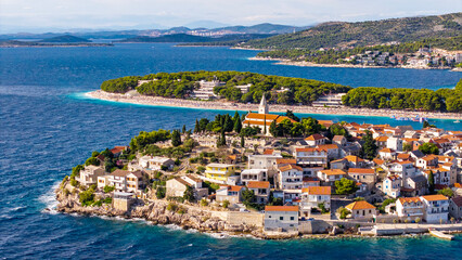 Fototapeta premium Aerial view of Primosten old town island in Croatia surrounded by Adriatic Sea turquoise water and summer sky