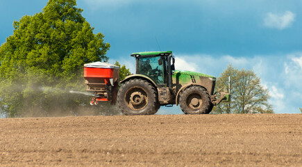 Obraz premium Tractor spreading fertilizer on farmland