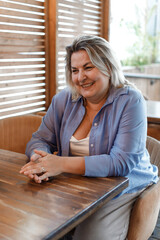 A smiling, plump businesswoman negotiates in a cafe.