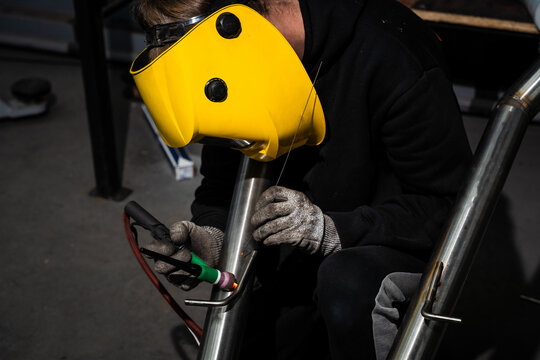 Argon-shielded TIG welding on custom automotive exhaust by welder