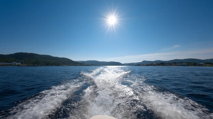A boat leaving a white wake on a deep blue sea under a bright sunny sky with coastal hills in the distance