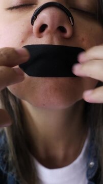 Latina woman using nasal strip and mouth tape for sleep and breathing - Biohacking and wellness. Vertical video
