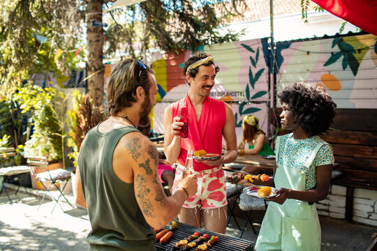 Friends grilling and chatting at backyard summer barbecue