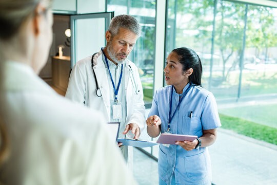 Doctor and nurse discussing patient chart in hospital corridor
