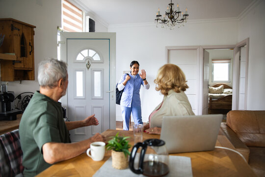 Home care nurse greeting senior couple at door