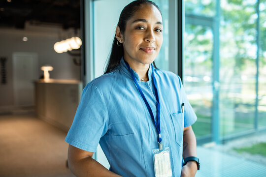 Confident nurse in blue scrubs in hospital corridor