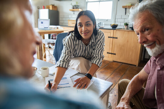Advisor helping senior couple with paperwork at home kitchen