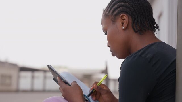 Student sketches designs outdoors. Creative student captures architectural concepts under sunlight. Determined student sketches detailed building ideas on rooftop during bright daylight