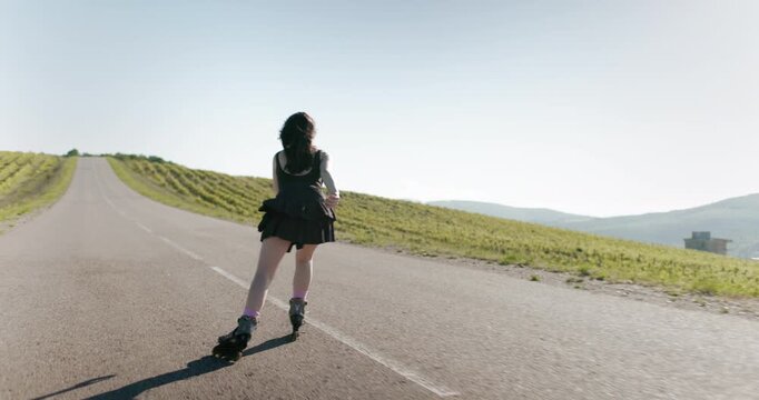 Sporty woman in black dress roller blading on road