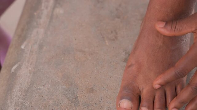 closeup bare foot on sand, gentle hand massage showing callused heel, slow comforting motion, warm natural light, outdoor concrete step, personal care, healing routine, tactile detail