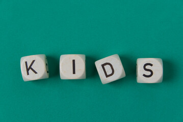 Cuatro dados que forman la palabra "kids", sobre fondo verde
