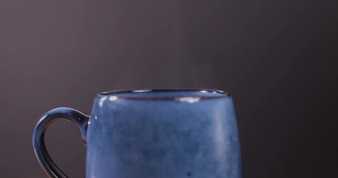 Steam rising from a hot drink in a cup against a dark background

