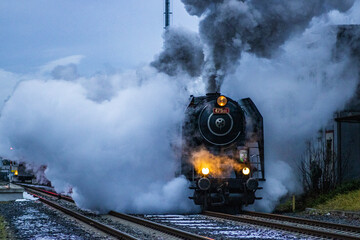 Naklejka premium evening departure of a steam locomotive in a cloud of smoke and steam