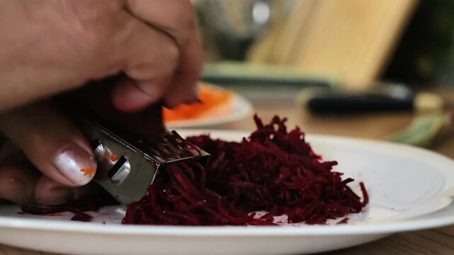 Hand grating fresh red beetroots for healthy food preparation