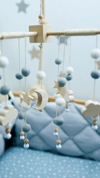 Cozy empty bed with soft sides for a baby boy. Nursery crib mobile of natural materials is hanging above the cot. Vertical video