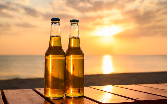 Two bottles of lager beer on the seashore. Sunset on the beach and beer.