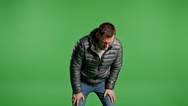 Man in pain, suffering from injury, holding his arm, green screen.