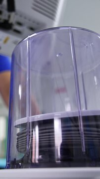 Pump of artificial ventilator machine raising inside the capsule. Doctor at backdrop is watching the work of equipment. Low angle view. Vertical video
