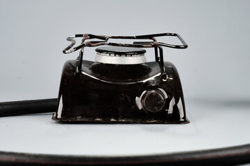 A sturdy black portable gas stove sits ready for use, displaying its single burner and control knob. A fuel hose extends from its side
