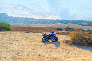 Obraz premium Parked quad near arid agricultural field with red soil, Ayia Napa, Cyprus