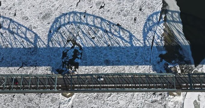 Traffic on bridge over a frozen river with ice floes.