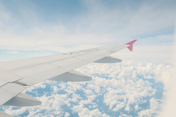 Obraz premium Airplane wing view above clouds with clear blue sky