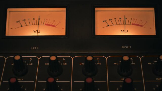 VU meters and mixing channels of an audio console. Symbol of music production, recording studio and live show broadcasting. A pro equipment video loop, with natural colors