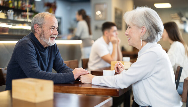 Mature couple communicate and chatting during date in cafe, have rendezvous, lovers tryst. Participants of meeting get to know each other, joke and communicate during meeting