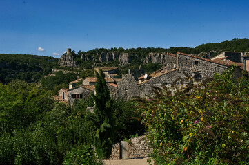 Traditional stone houses in the medieval village of Balazuc, Ardeche, France. A view of ancient masonry architecture against limestone cliffs and a clear blue sky.