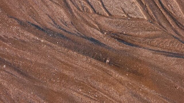 Magical with Black Sand Beaches on multicolored Hormuz Island, Iran. The dark sand from heavy minerals such as hematite, ilmenite, and magnetite, creating striking textures along the shoreline.