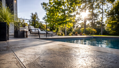 Stamped concrete patio near a pool with chairs and sunlight