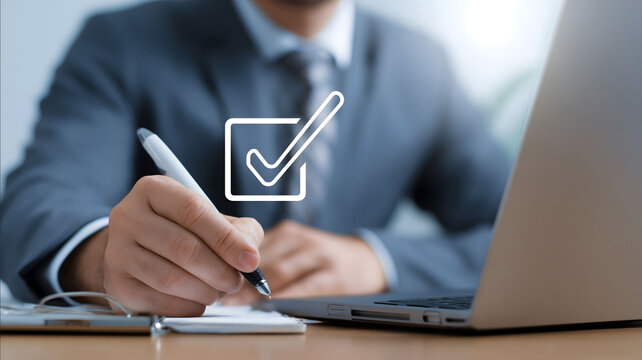 A man in business attire sits at his laptop holding an ink pen and a checkmark icon hovering above the screen