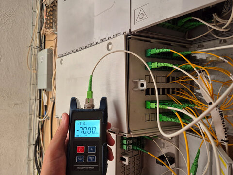 The internet technician measures signal strength using power measurement tools to accurately measure light intensity. Power measurement in telecommunications boxes. Optical terminal box. CTO.