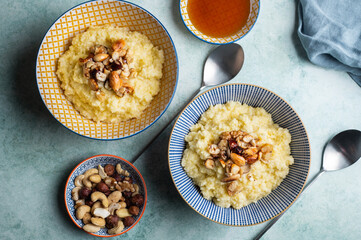 Delicious healthy breakfast: millet porridge cooked with coconut milk and toped up with caramelised mixed nuts and maple syrup
