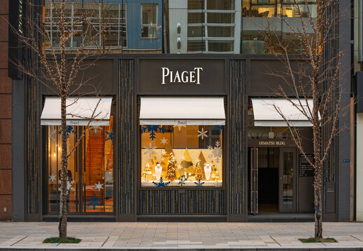 tokyo, ginza - jan 08 2025: A Japanese sidewalk view of the Swiss brand Piaget boutique, showing festive gold Christmas trees and snowflakes behind large glass windows during the clear winter season.