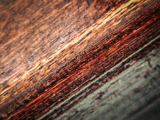 Fototapeta premium Close-up view of textured wooden surface showcasing rich brown and green hues with visible grain patterns and natural imperfections in a rustic style
