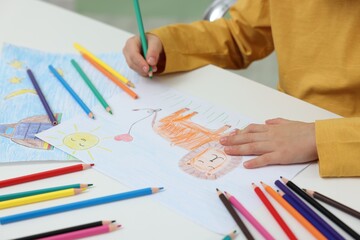 Little boy drawing lion with pencil at table, closeup
