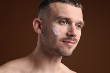 Obraz premium Handsome man with cream on his face against brown background